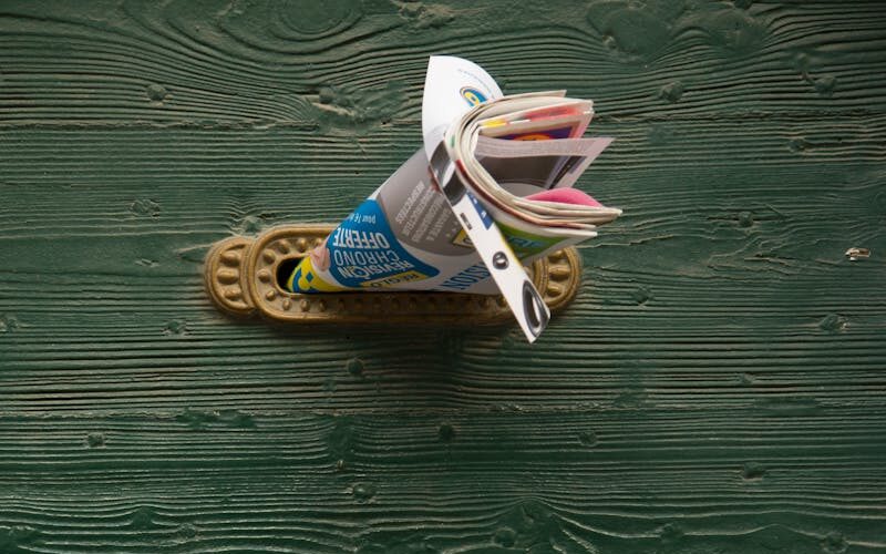 Advertising leaflets on green wooden door with vintage knocker.